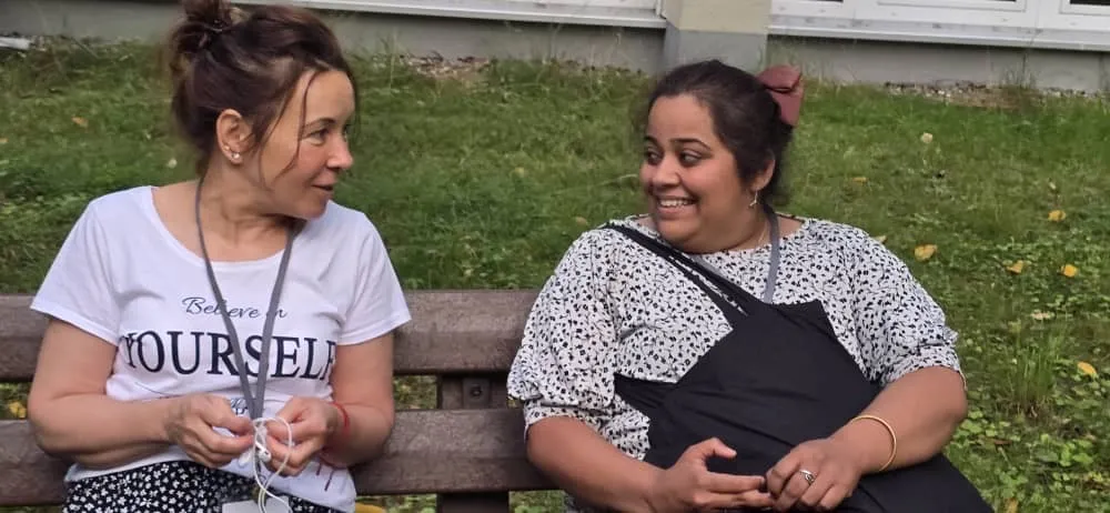 Priya laughing with a friend on a park bench